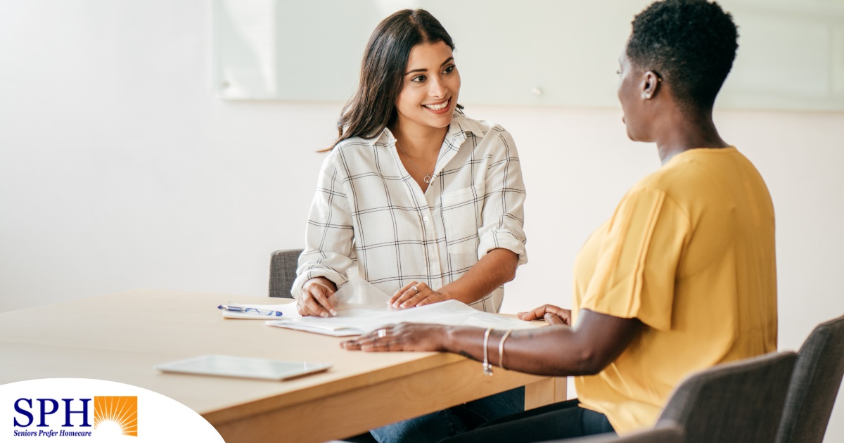 A woman happily interviews another woman, representing how well caregiver interviews can go when prepared.