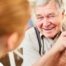 A caregiver holds hands with a happy older client, representing the results of creating a comfortable environment in the home.