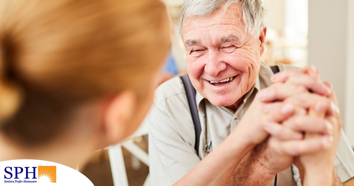 A caregiver holds hands with a happy older client, representing the results of creating a comfortable environment in the home.